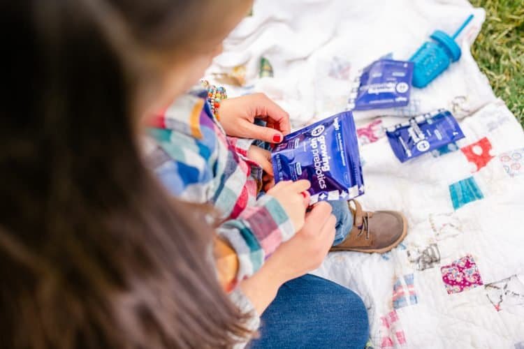 A child handles blue Begin Health packets on a picnic blanket.