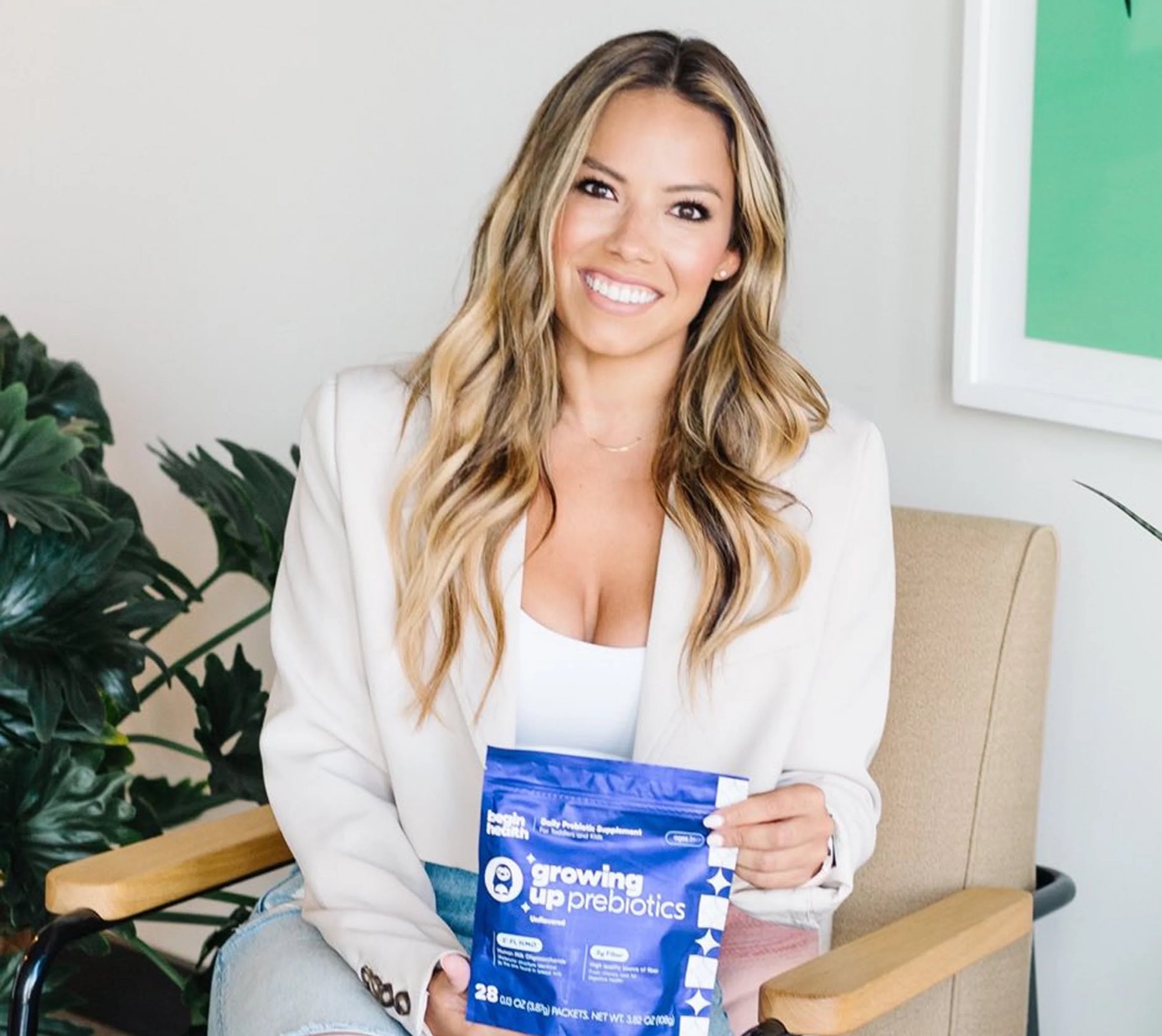 A seated woman presents a blue Growing Up Prebiotics pouch.