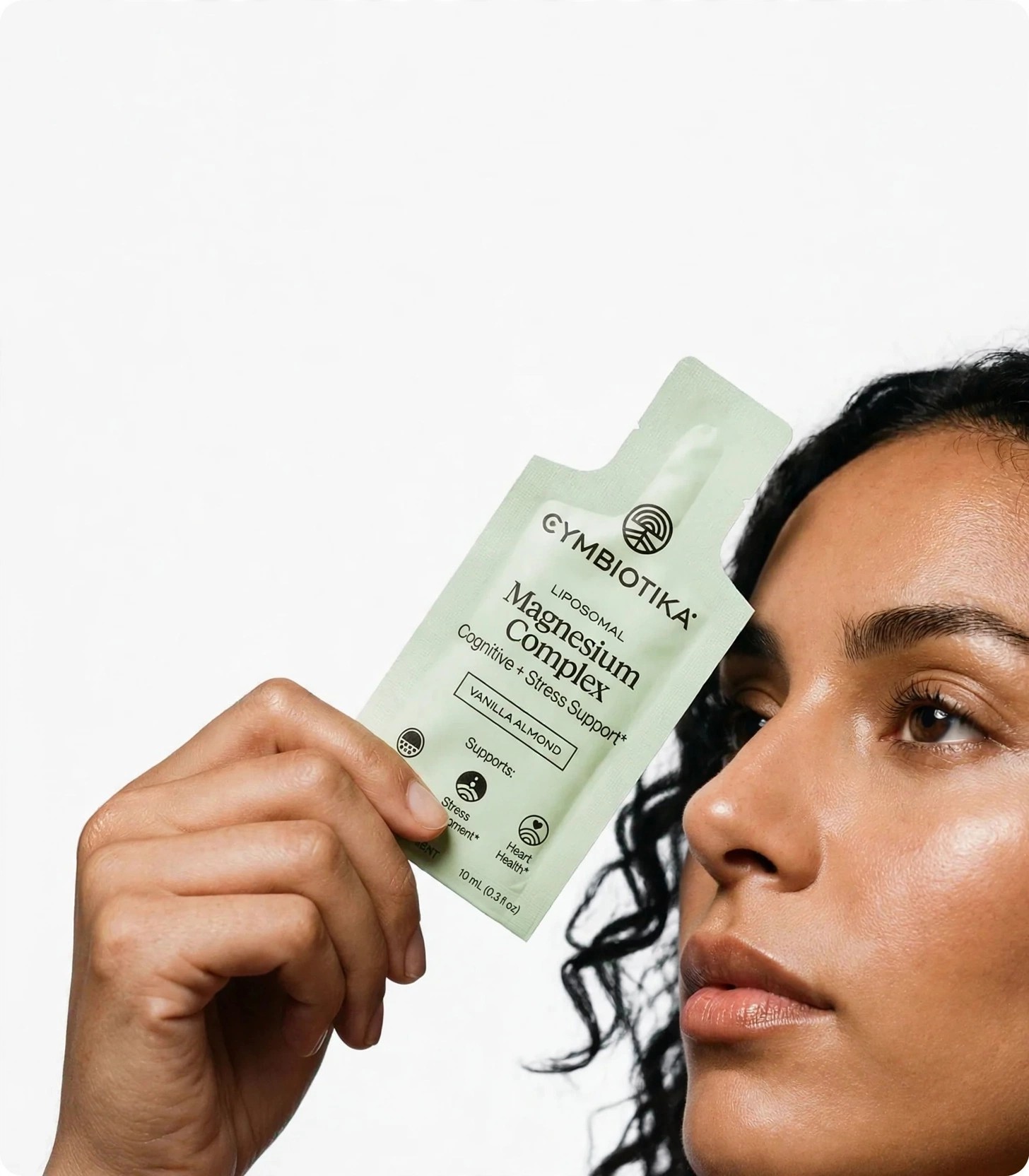 Woman holds a light green supplement pouch near her face.