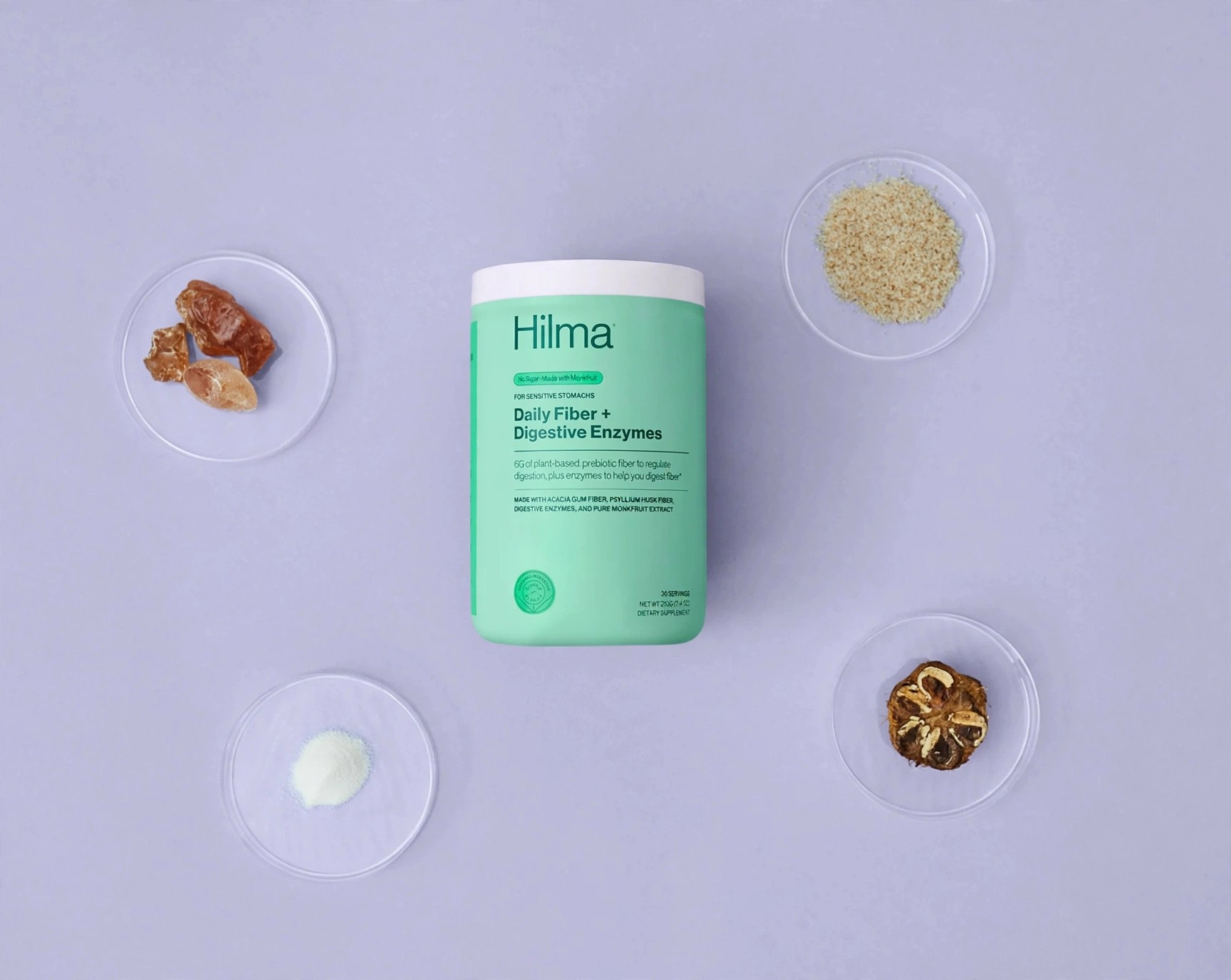Hilma Daily Fiber canister centered among small dishes of ingredients.