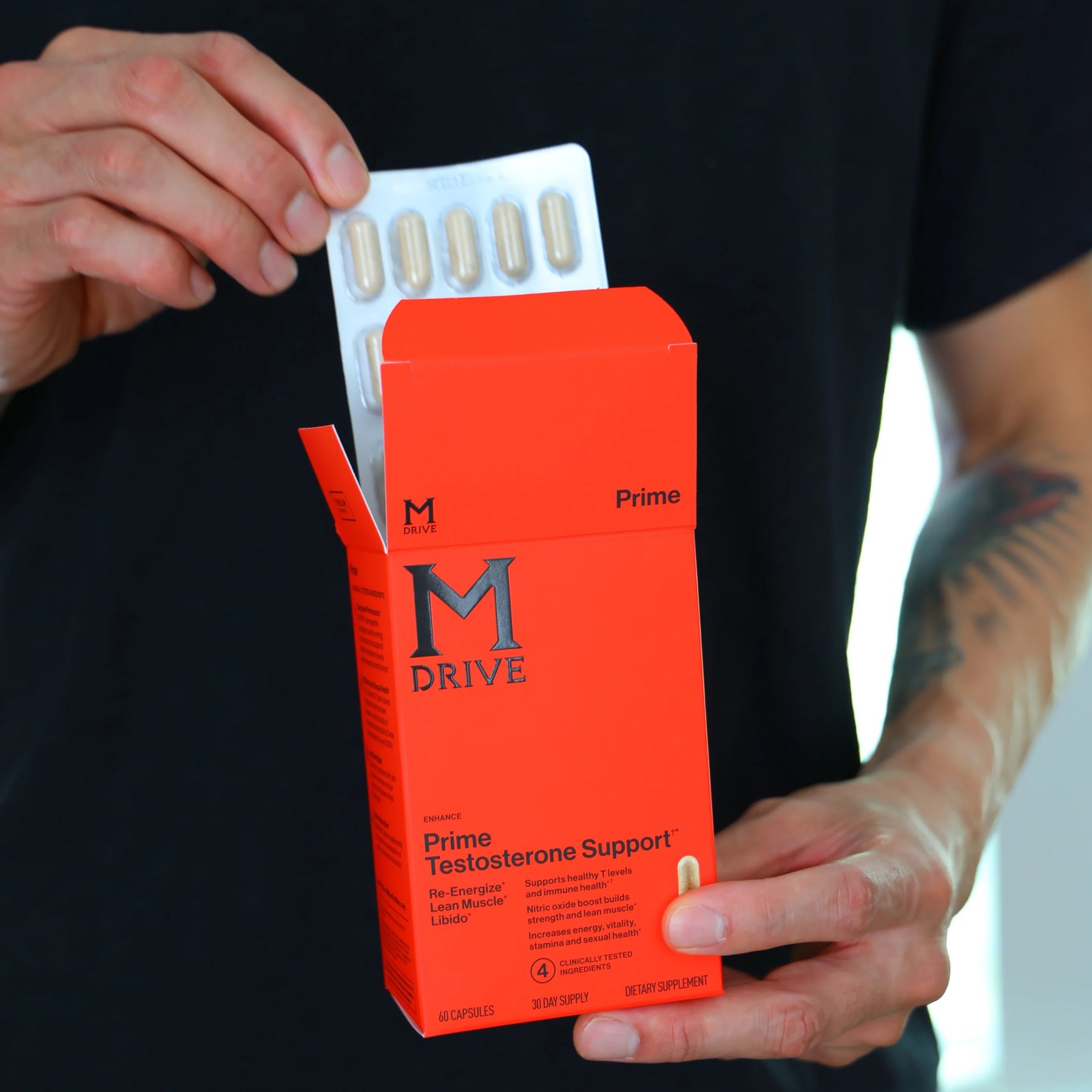 Hands pull a blister of capsules from the orange Prime box.
