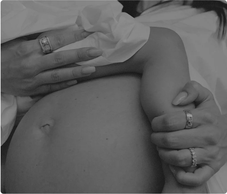 Two hands gently cradling a pregnant belly.