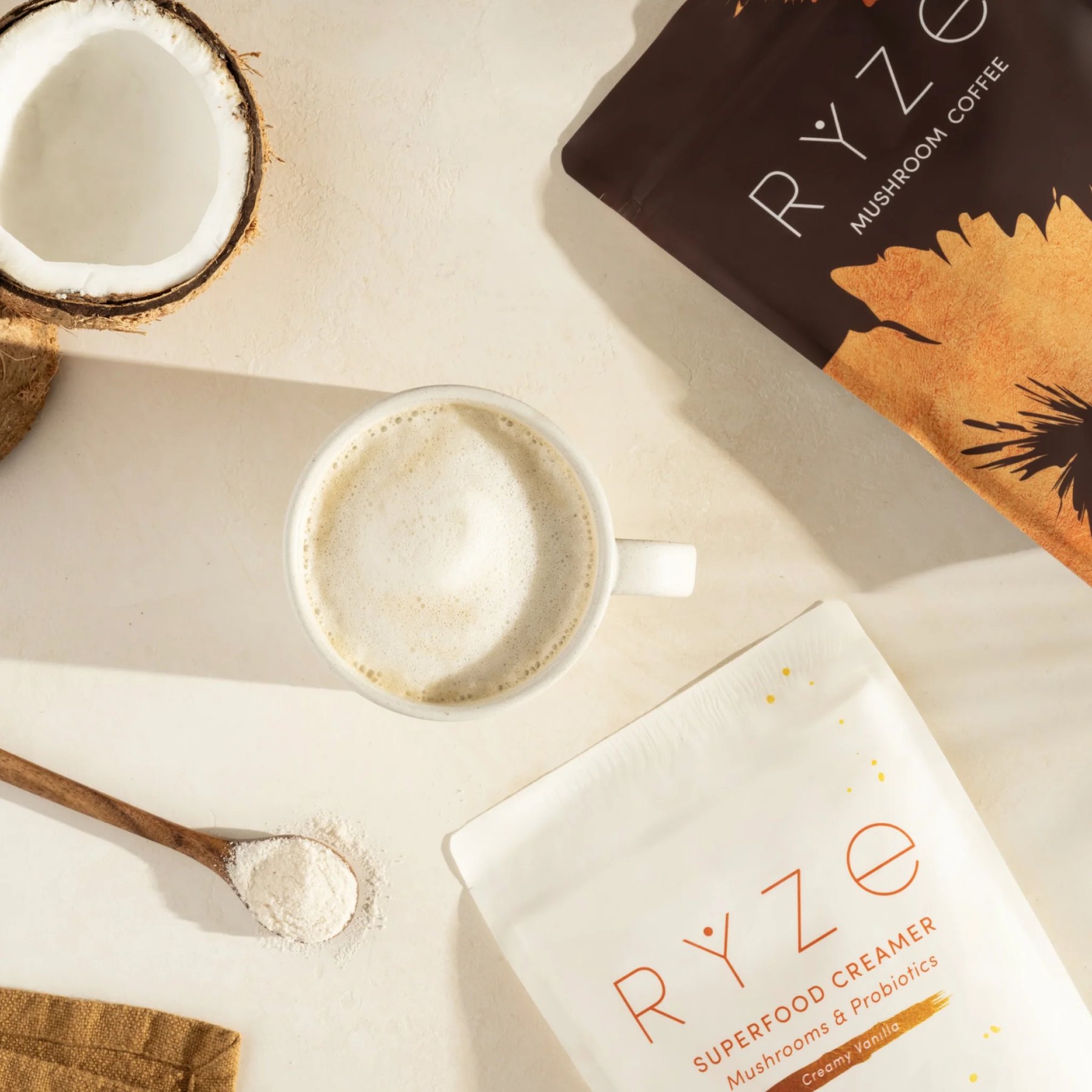 Overhead view of a frothy mug beside RYZE coffee and creamer.