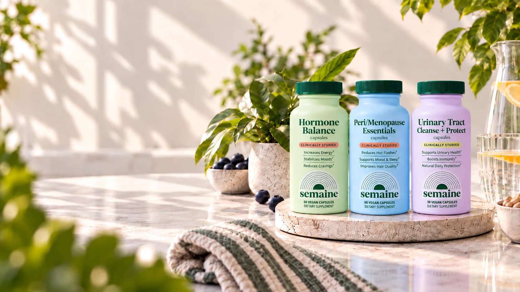 Three Semaine bottles styled on a marble counter with greenery.